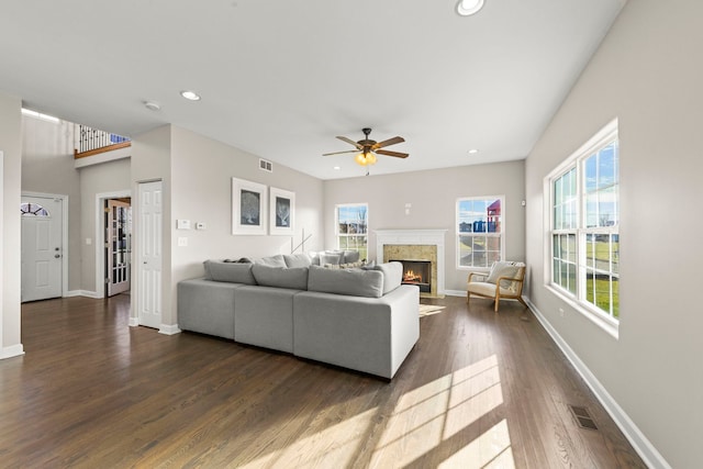 living area featuring visible vents, ceiling fan, a high end fireplace, and dark wood finished floors