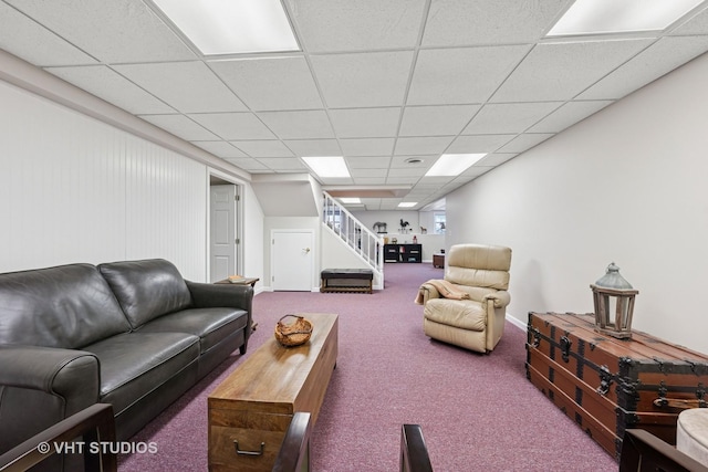 carpeted living area with a drop ceiling and stairway