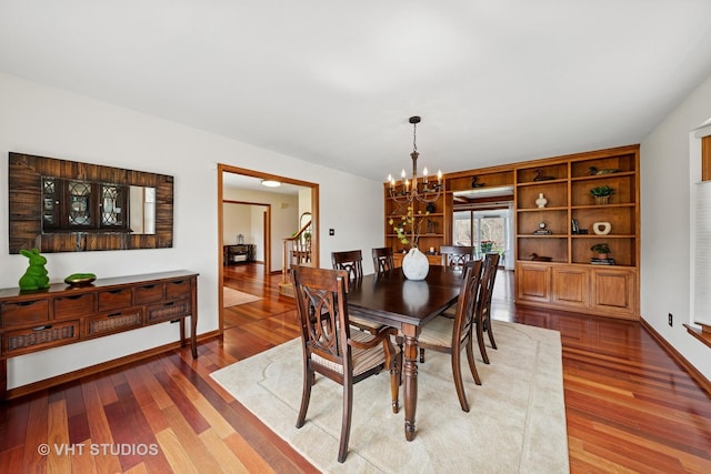 dining space featuring baseboards, an inviting chandelier, and wood finished floors