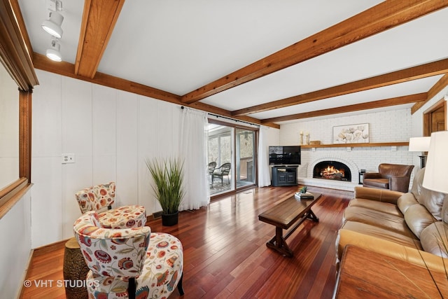 living room with beam ceiling, hardwood / wood-style floors, and a fireplace
