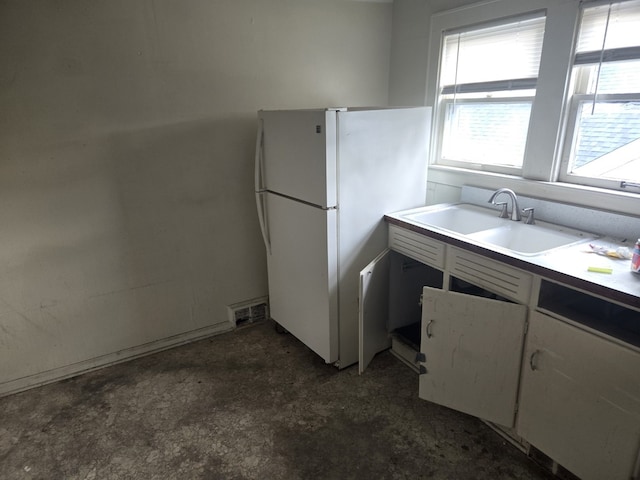 708 W Jefferson St W, Bloomington, IL 61701 - kitchen featuring a sink, concrete flooring, freestanding refrigerator, and white cabinets