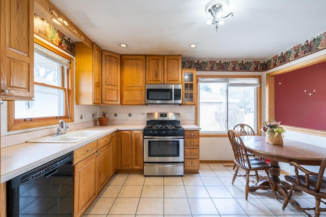 kitchen featuring light countertops, brown cabinets, tasteful backsplash, appliances with stainless steel finishes, and a sink