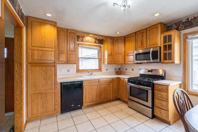 kitchen with light countertops, stainless steel appliances, tasteful backsplash, glass insert cabinets, and a sink