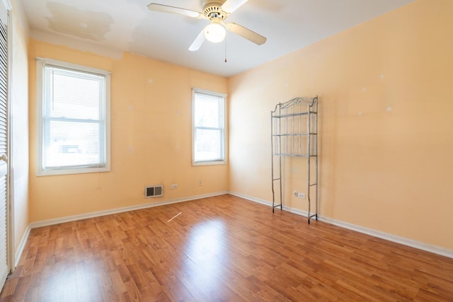 unfurnished room with baseboards, visible vents, wood finished floors, and a ceiling fan