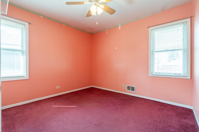 carpeted empty room featuring baseboards, visible vents, and a ceiling fan