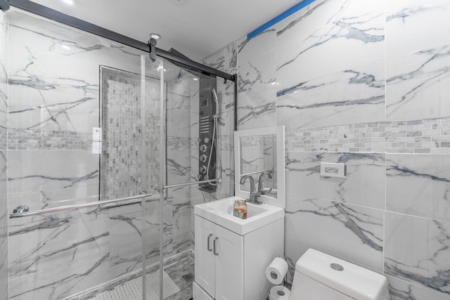 bathroom with tile walls, a marble finish shower, toilet, and vanity
