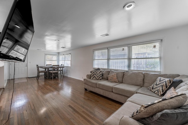 living area with baseboards, visible vents, and hardwood / wood-style floors