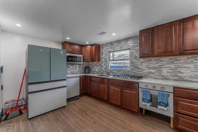 kitchen with light countertops, visible vents, wood finished floors, tasteful backsplash, and appliances with stainless steel finishes