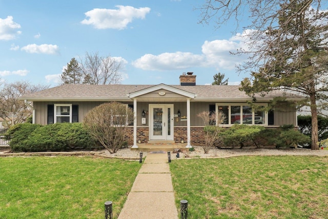 ranch-style home with board and batten siding, a chimney, a front yard, and brick siding