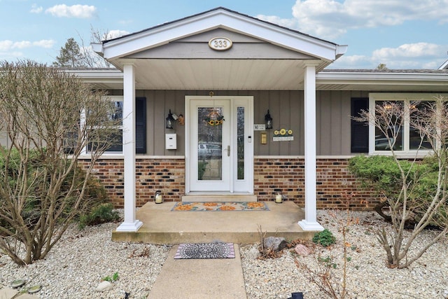 property entrance with board and batten siding, brick siding, and covered porch