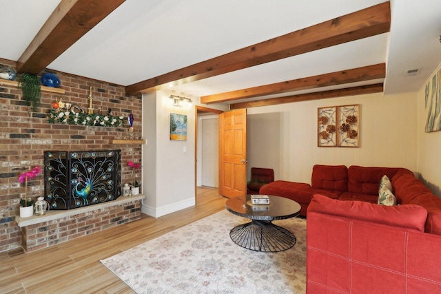 living room featuring wood finished floors, beamed ceiling, a fireplace, and visible vents