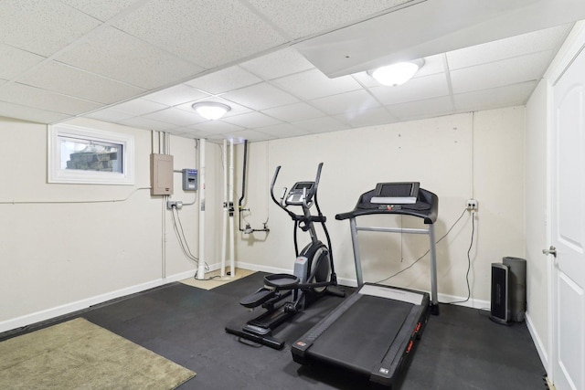 exercise area featuring a paneled ceiling and baseboards