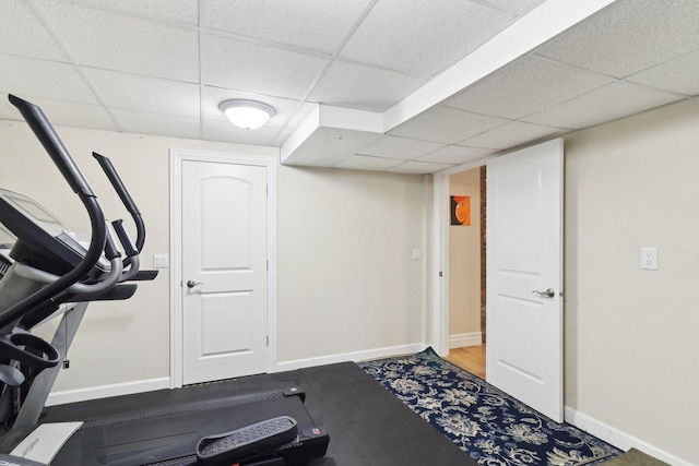 exercise room with a paneled ceiling and baseboards
