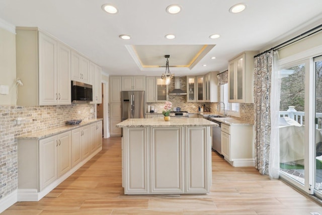 kitchen featuring a center island, a sink, stainless steel appliances, a raised ceiling, and decorative backsplash
