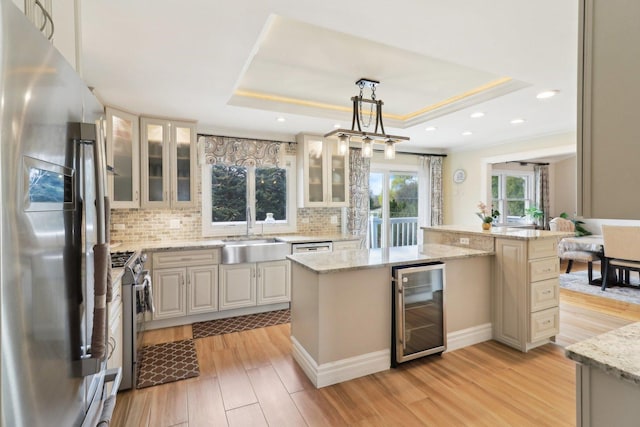 kitchen with a raised ceiling, decorative backsplash, stainless steel appliances, beverage cooler, and a sink