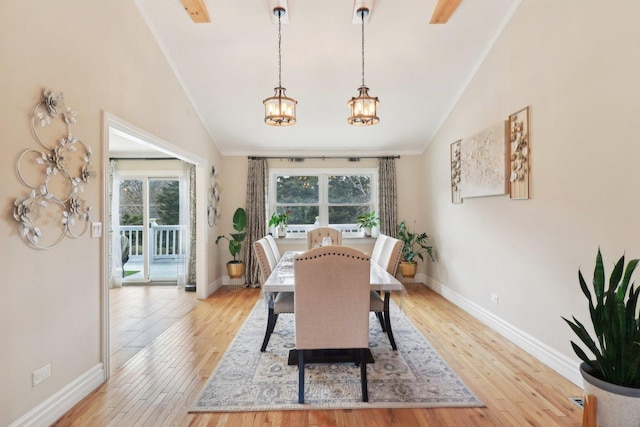 dining room with light wood-style flooring, an inviting chandelier, baseboards, and lofted ceiling