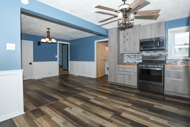 114 W Columbia St, Danvers, IL 61732 - kitchen featuring wainscoting, dark wood finished floors, ceiling fan with notable chandelier, stainless steel appliances, and tasteful backsplash