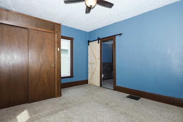 114 W Columbia St, Danvers, IL 61732 - unfurnished bedroom with visible vents, baseboards, a barn door, a textured ceiling, and carpet flooring