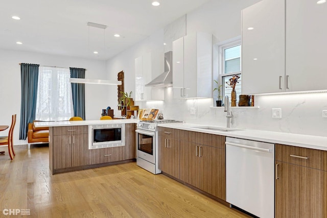 kitchen featuring white range with gas cooktop, a peninsula, built in microwave, dishwasher, and a sink