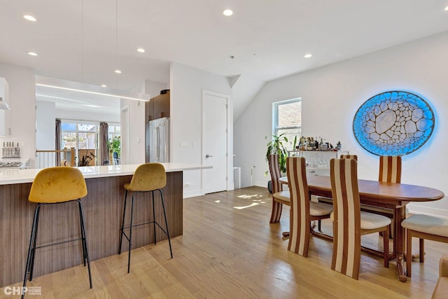 kitchen featuring high end fridge, light countertops, a kitchen breakfast bar, and light wood-style floors