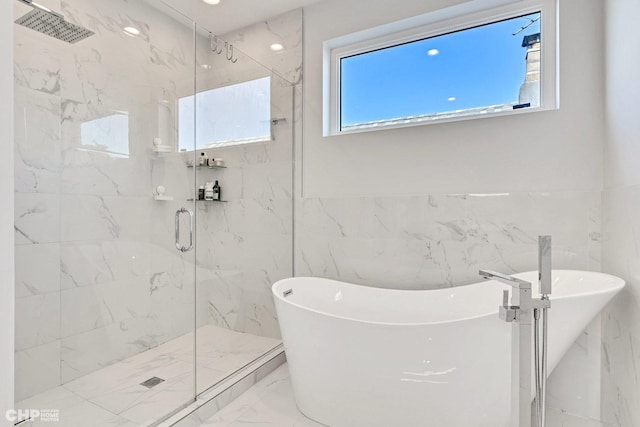 bathroom featuring tile walls, a freestanding tub, marble finish floor, and a marble finish shower