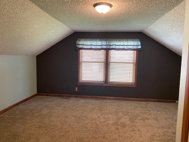 bonus room with baseboards, carpet flooring, lofted ceiling, and a textured ceiling