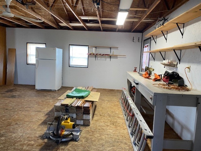 basement featuring freestanding refrigerator and a workshop area