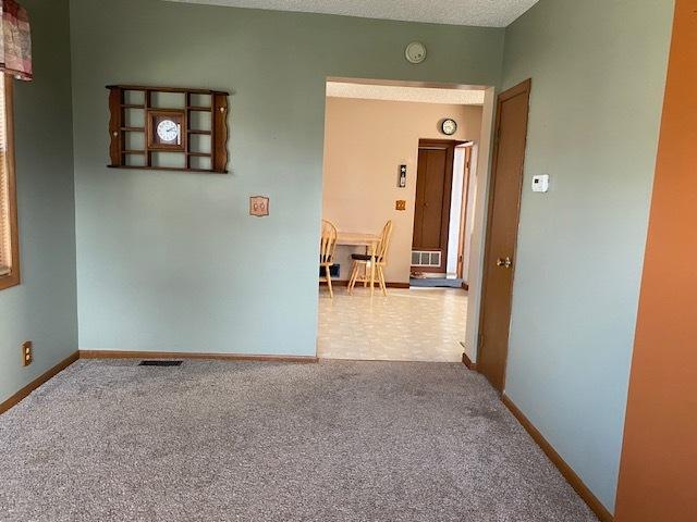 carpeted empty room featuring baseboards and visible vents