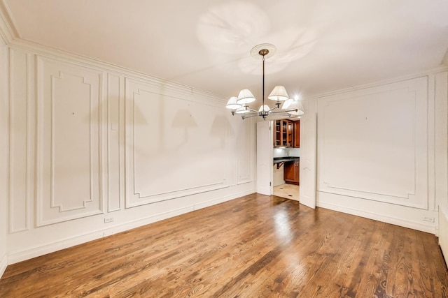 unfurnished dining area featuring an inviting chandelier, dark wood-style flooring, and a decorative wall