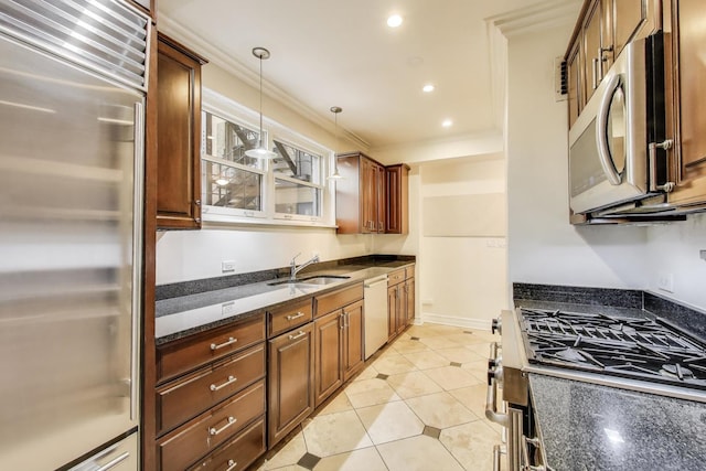 kitchen featuring appliances with stainless steel finishes, a sink, ornamental molding, dark stone countertops, and pendant lighting
