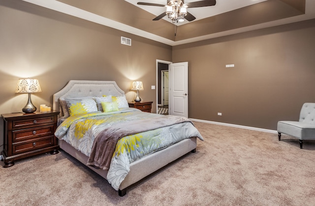 bedroom with visible vents, baseboards, a raised ceiling, ceiling fan, and carpet