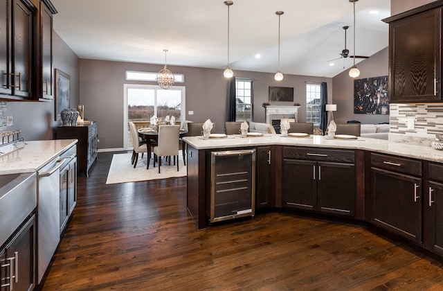 kitchen with open floor plan, dark wood-style floors, dark brown cabinets, wine cooler, and a fireplace