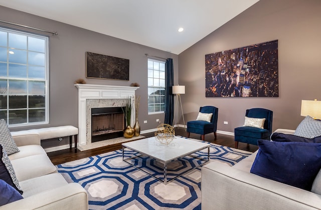 living area with recessed lighting, wood finished floors, lofted ceiling, a high end fireplace, and baseboards