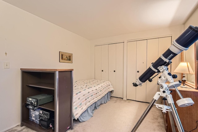bedroom with multiple closets and carpet flooring