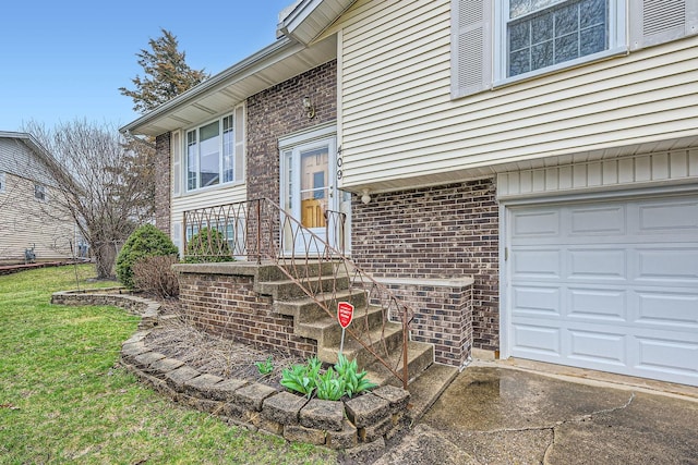 doorway to property with a lawn, an attached garage, brick siding, and concrete driveway