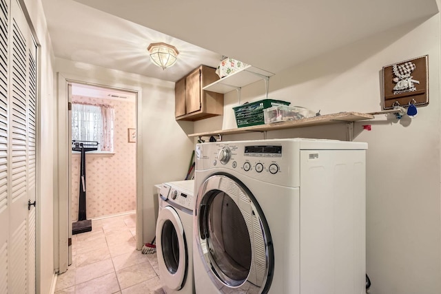 clothes washing area featuring washer and clothes dryer, baseboards, wallpapered walls, light tile patterned flooring, and cabinet space