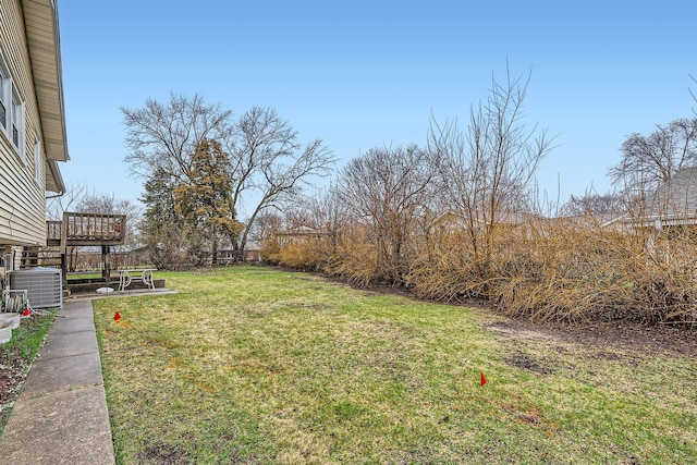 view of yard with central air condition unit and a deck