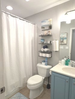 half bath with vanity, toilet, baseboards, visible vents, and wood finished floors