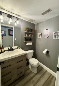 bathroom featuring vanity, toilet, baseboards, visible vents, and wood finished floors