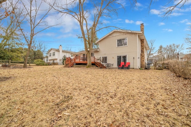 rear view of house with fence, a deck, and a chimney