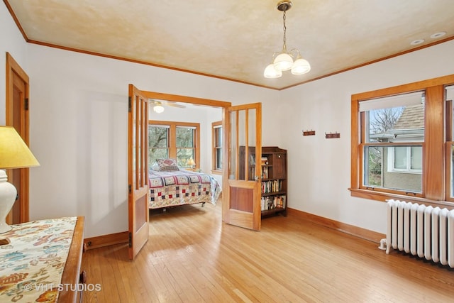 bedroom with radiator heating unit, multiple windows, light wood-type flooring, and baseboards