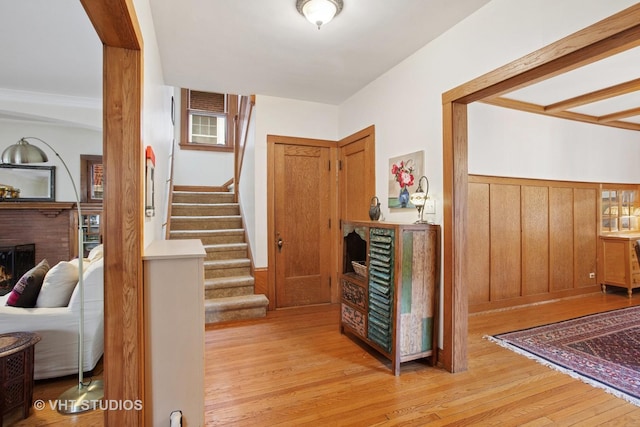 interior space featuring stairway, wainscoting, light wood-style floors, and a fireplace
