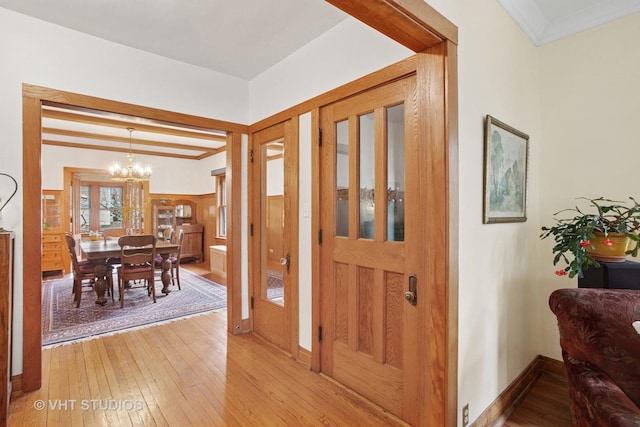 foyer featuring light wood-style flooring, baseboards, an inviting chandelier, and crown molding
