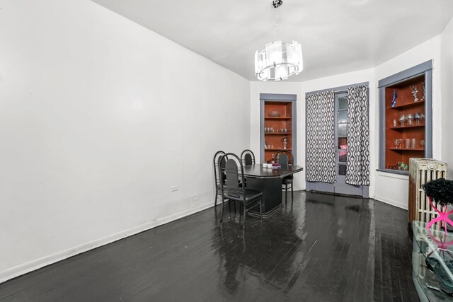 4734 W Monroe St, Chicago, IL 60644 - dining area featuring a notable chandelier, baseboards, built in shelves, and wood finished floors