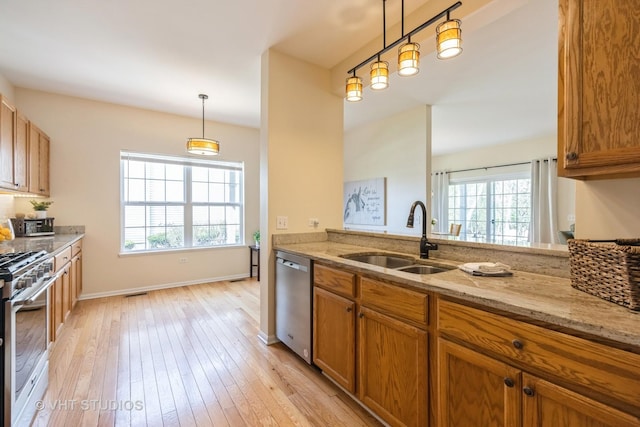 kitchen with a sink, appliances with stainless steel finishes, plenty of natural light, and brown cabinetry