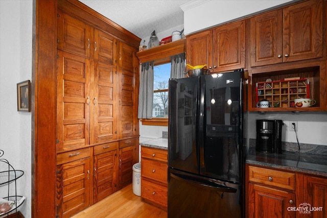 416 Stilson St, Earlville, IL 60518 - kitchen featuring light wood finished floors, brown cabinets, dark stone counters, and freestanding refrigerator