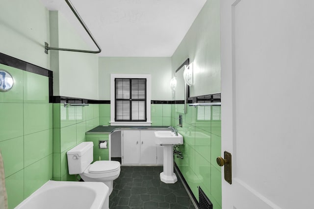 bathroom featuring visible vents, toilet, tile walls, a bathtub, and tile patterned flooring