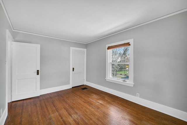 unfurnished room featuring wood-type flooring, visible vents, baseboards, and ornamental molding