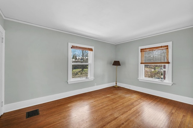 empty room with wood-type flooring, ornamental molding, visible vents, and plenty of natural light