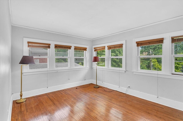 unfurnished room with light wood-style floors, crown molding, and baseboards